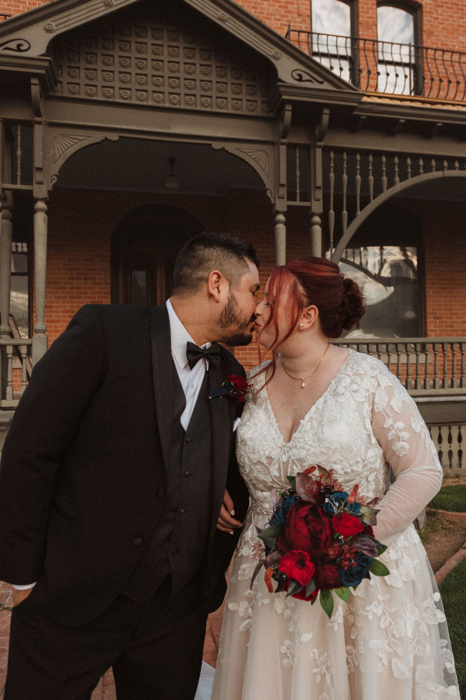 A tender wedding moment captured on the porch of a historic Victorian house.