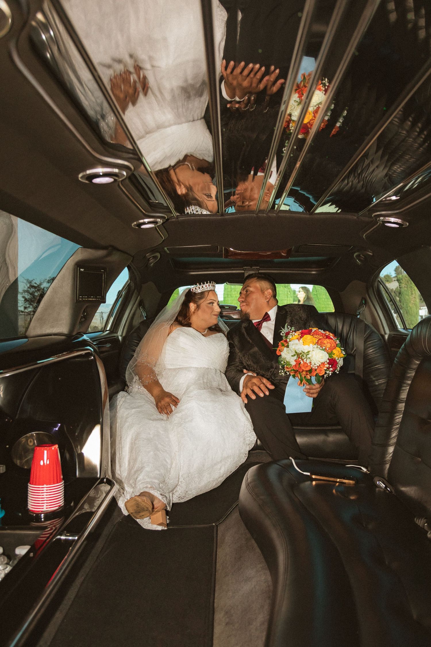 Wedding couple relaxing in the spacious interior of their limousine with mirrored ceiling.