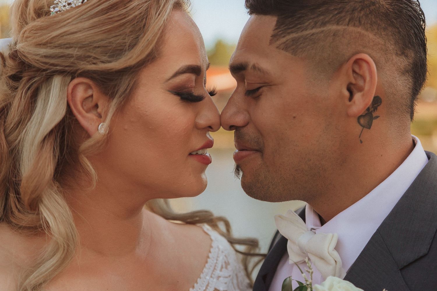 Intimate close-up of wedding couple sharing tender moment with lake in background.