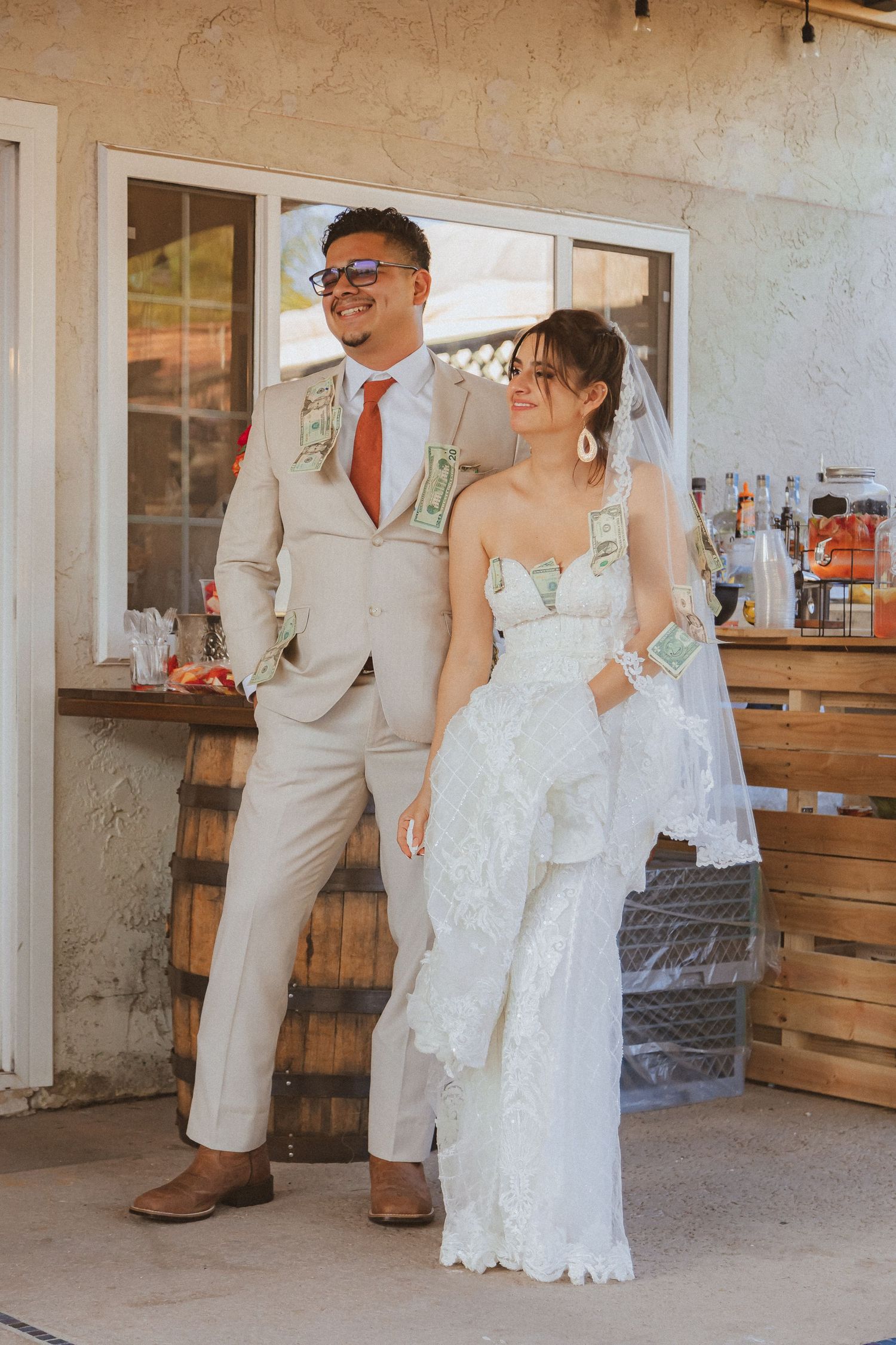 A bride and groom pose together at their rustic outdoor wedding venue.