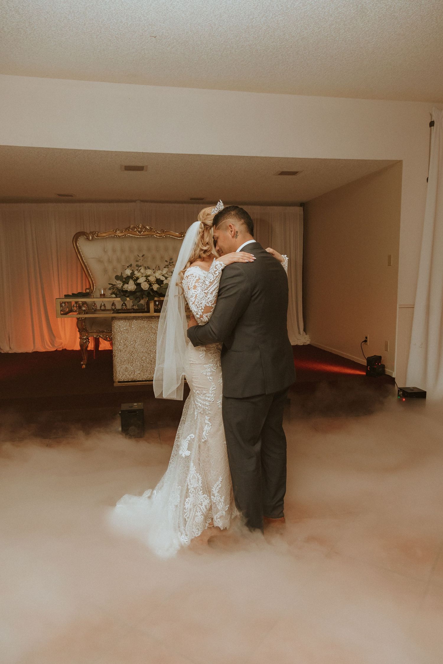 An intimate wedding moment captured with atmospheric fog and warm lighting.