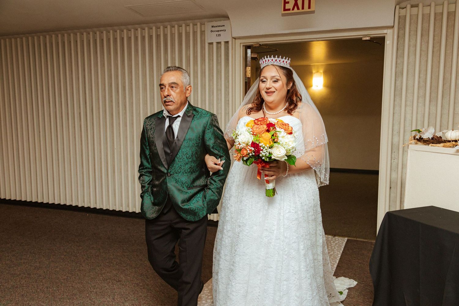 Wedding processional in indoor venue with decorative white aisle runner.