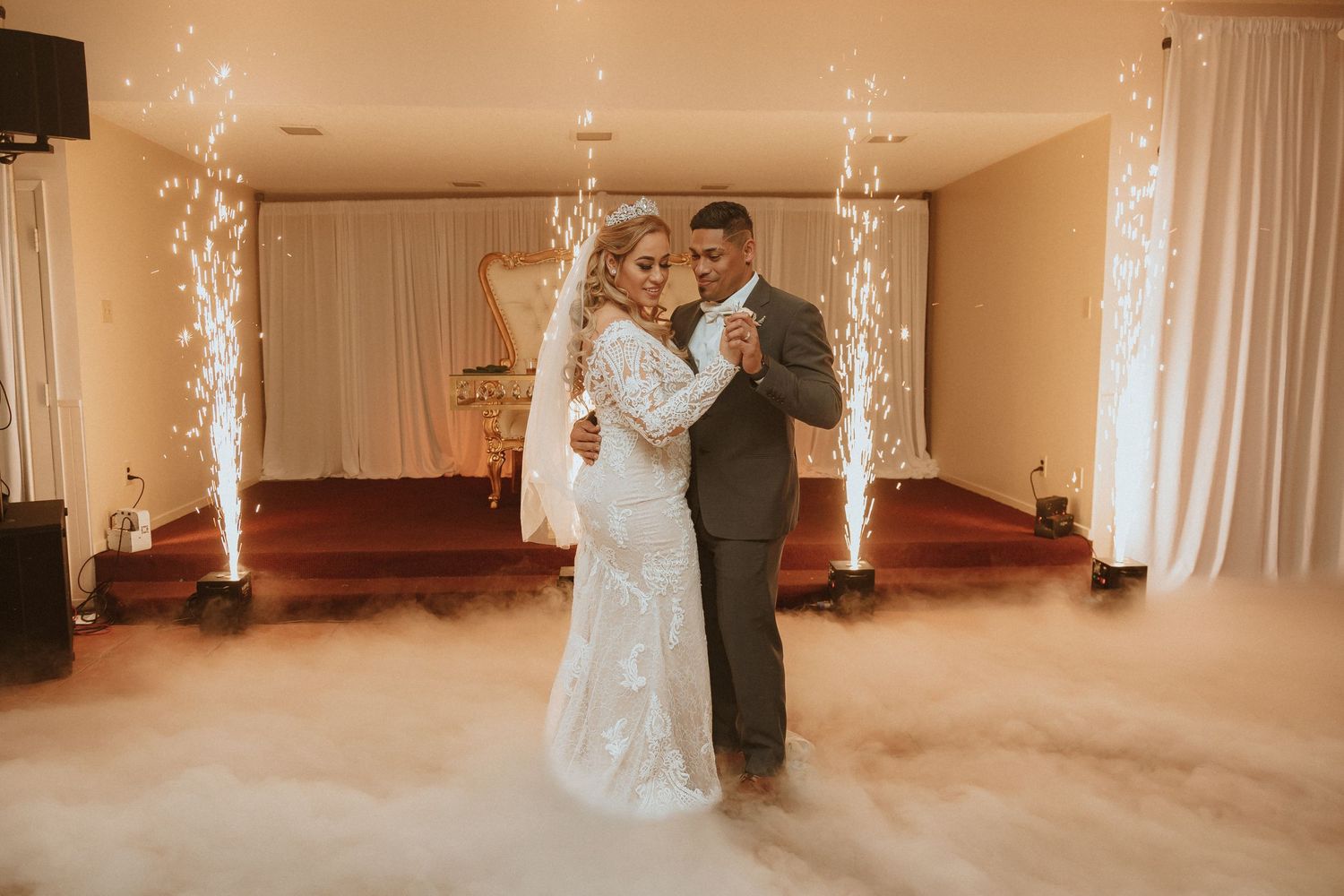 Couple sharing an intimate dance moment on their wedding day surrounded by sparklers and elegant white drapes.