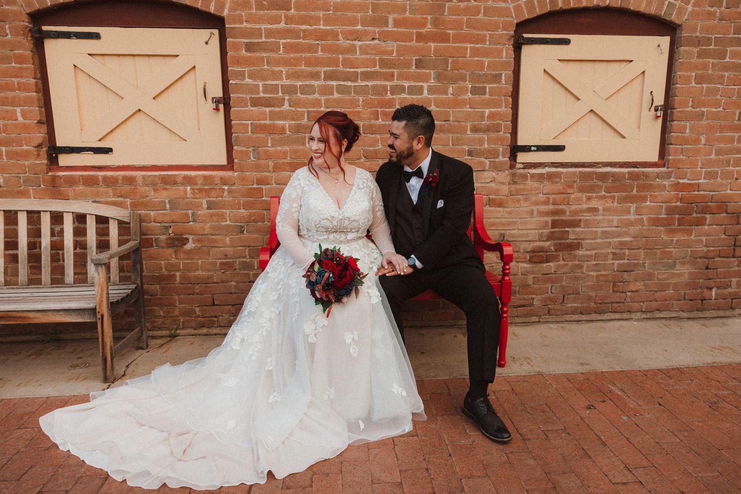 A wedding portrait against rustic wooden doors and brick walls with vintage charm.