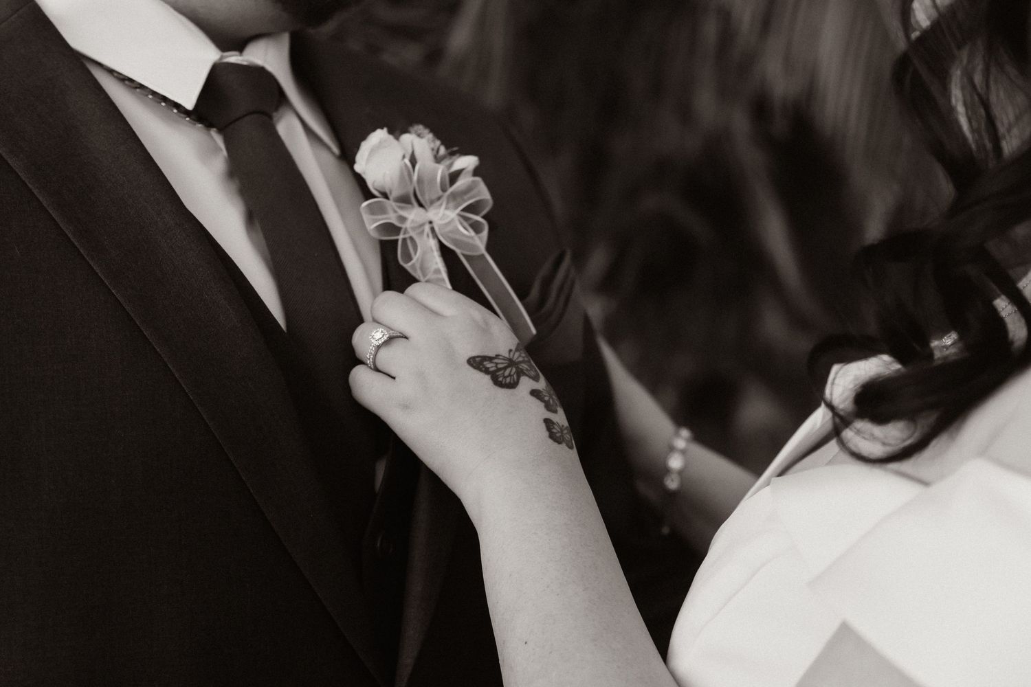 Close-up shot of hands pinning boutonniere on groom's lapel.