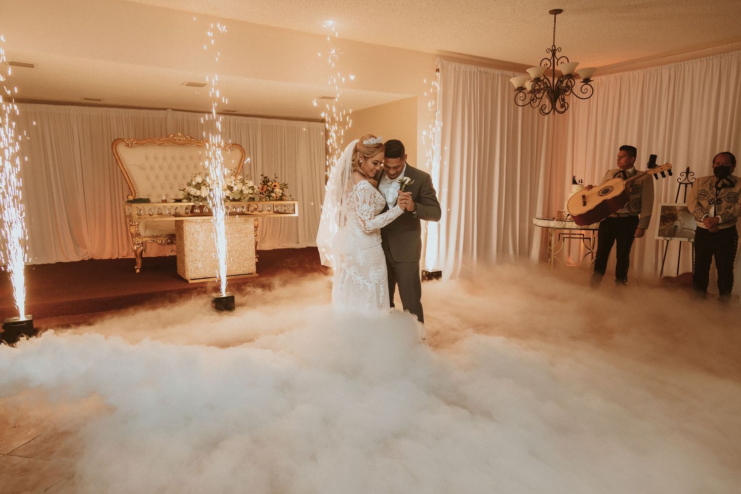 Romantic first dance moment captured with low-lying fog and dramatic sparkler effects in wedding venue.
