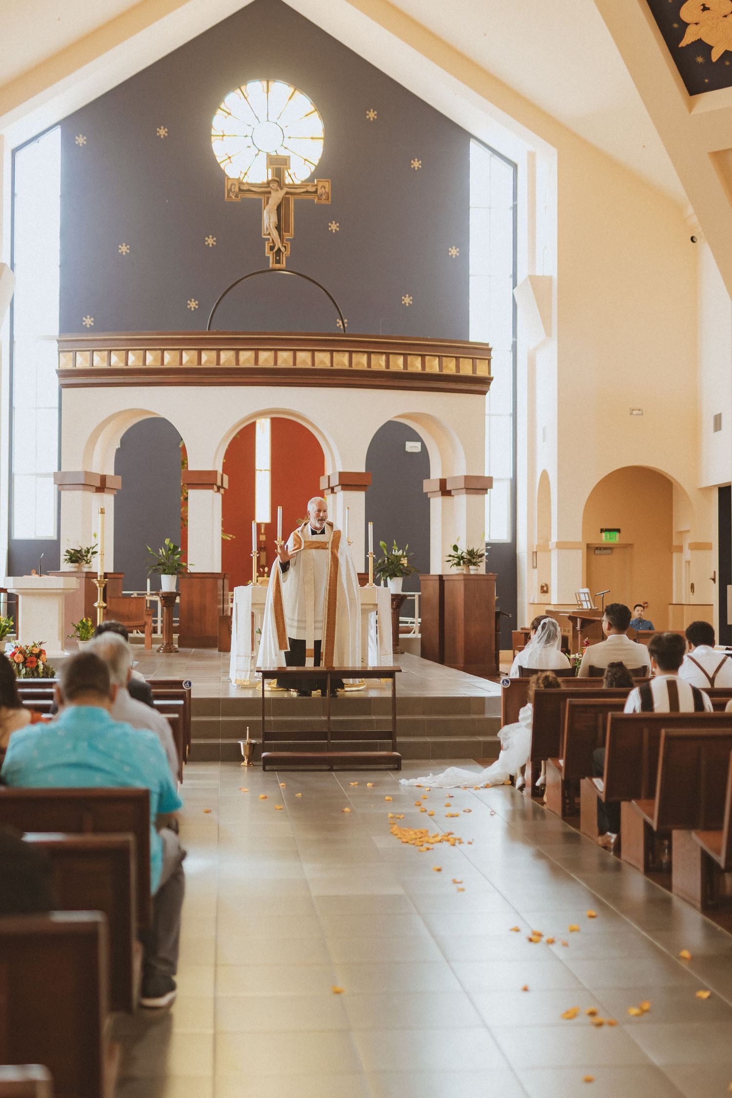 Interior of a church sanctuary with crucifix mounted high above altar during a ceremony.