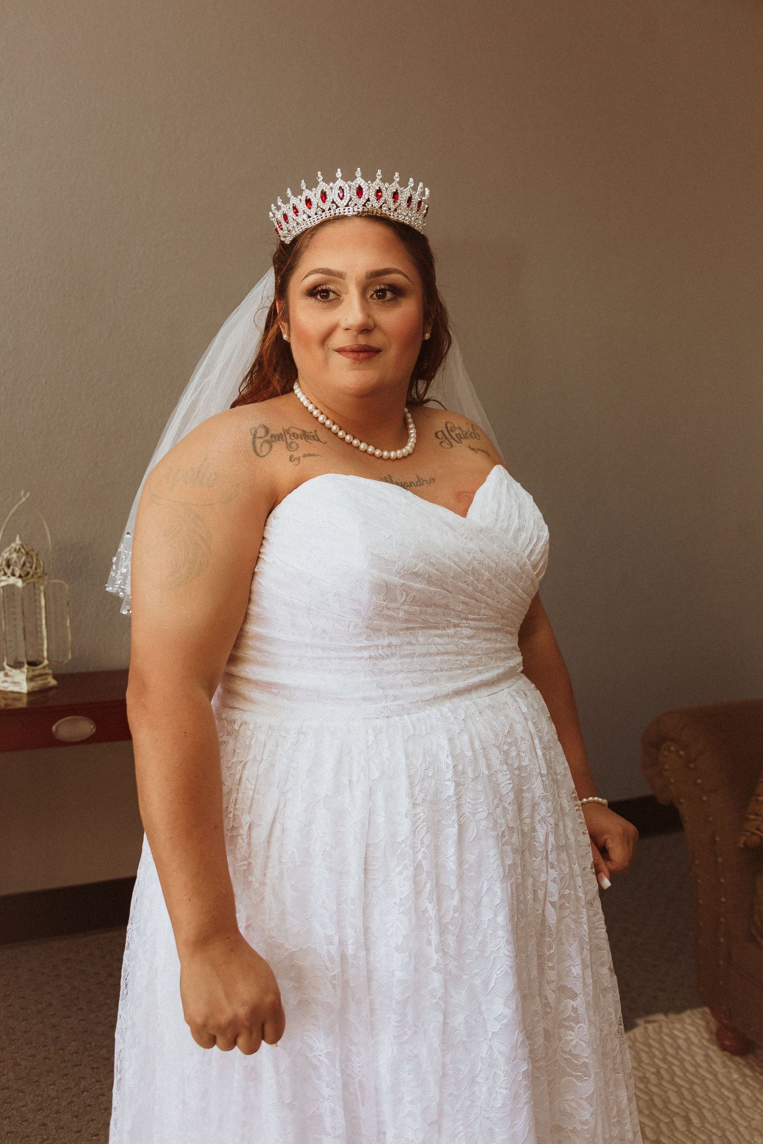 A bride in a strapless white gown wears a sparkling tiara and pearl necklace on her wedding day.