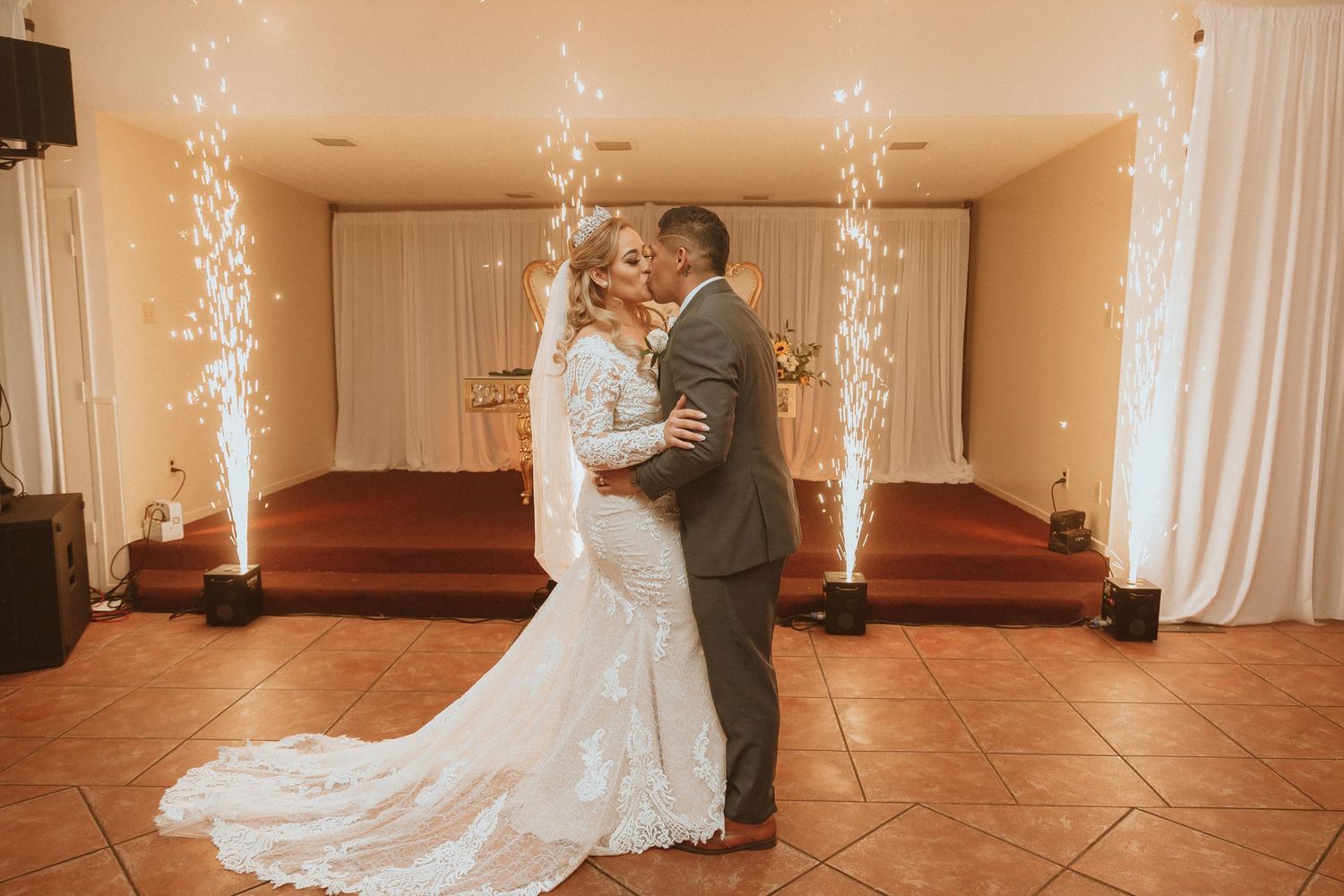 A beautiful wedding moment captured with the couple dancing in a warmly lit room with sparkling fountains.