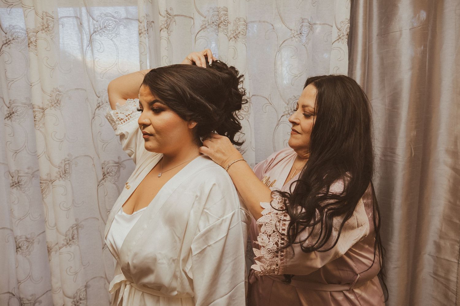 Bridesmaids help style the bride's hair during wedding preparations.