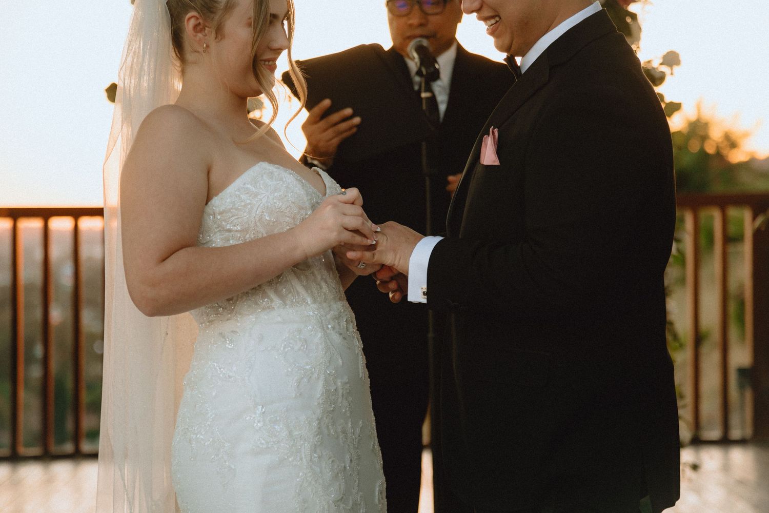 Close-up shot of wedding ring exchange during an outdoor ceremony at golden hour.