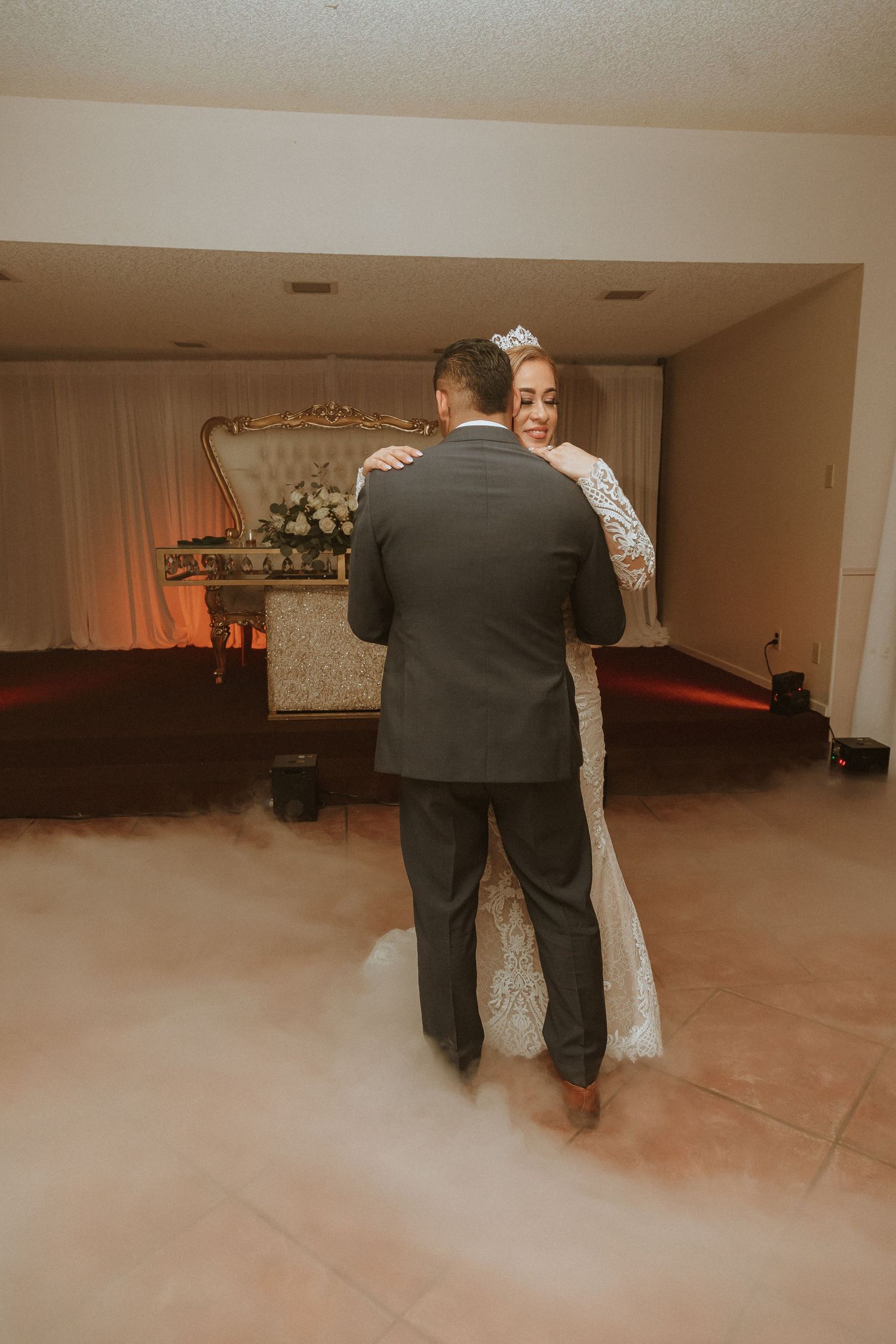 A tender wedding dance moment captured with atmospheric fog effects on the dance floor.
