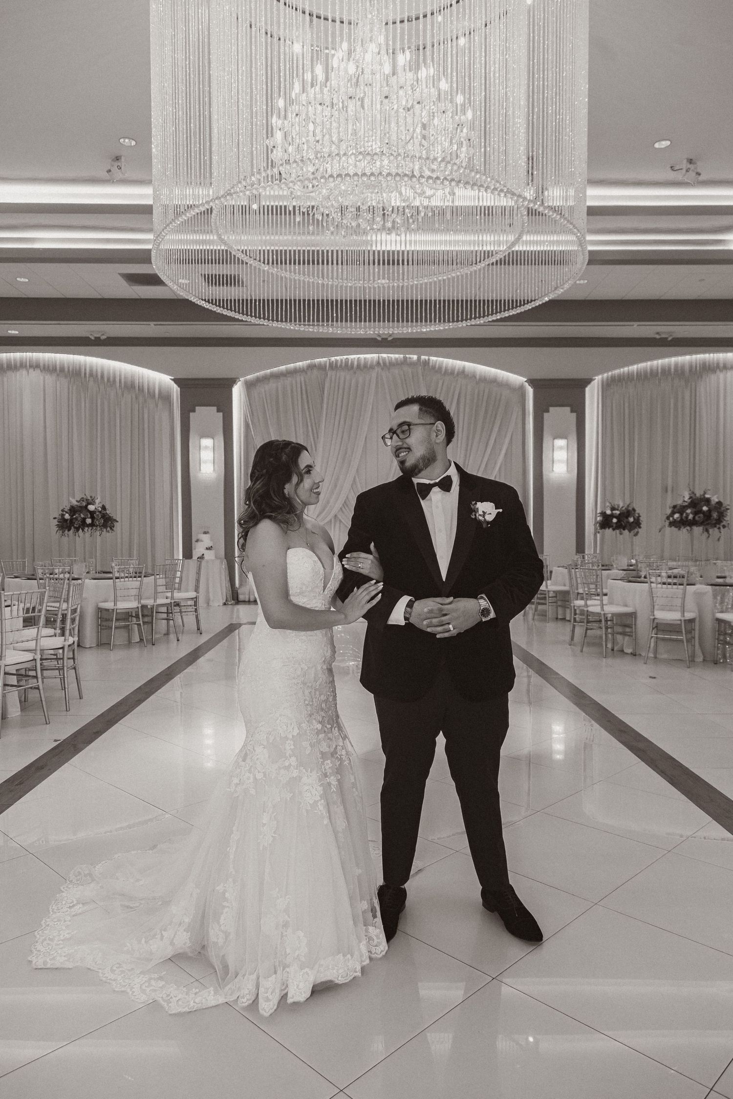 Elegant wedding portrait under crystal chandelier in luxurious reception venue.