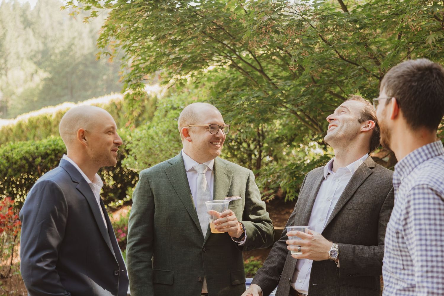 Four guests share drinks and conversation during an outdoor garden gathering.