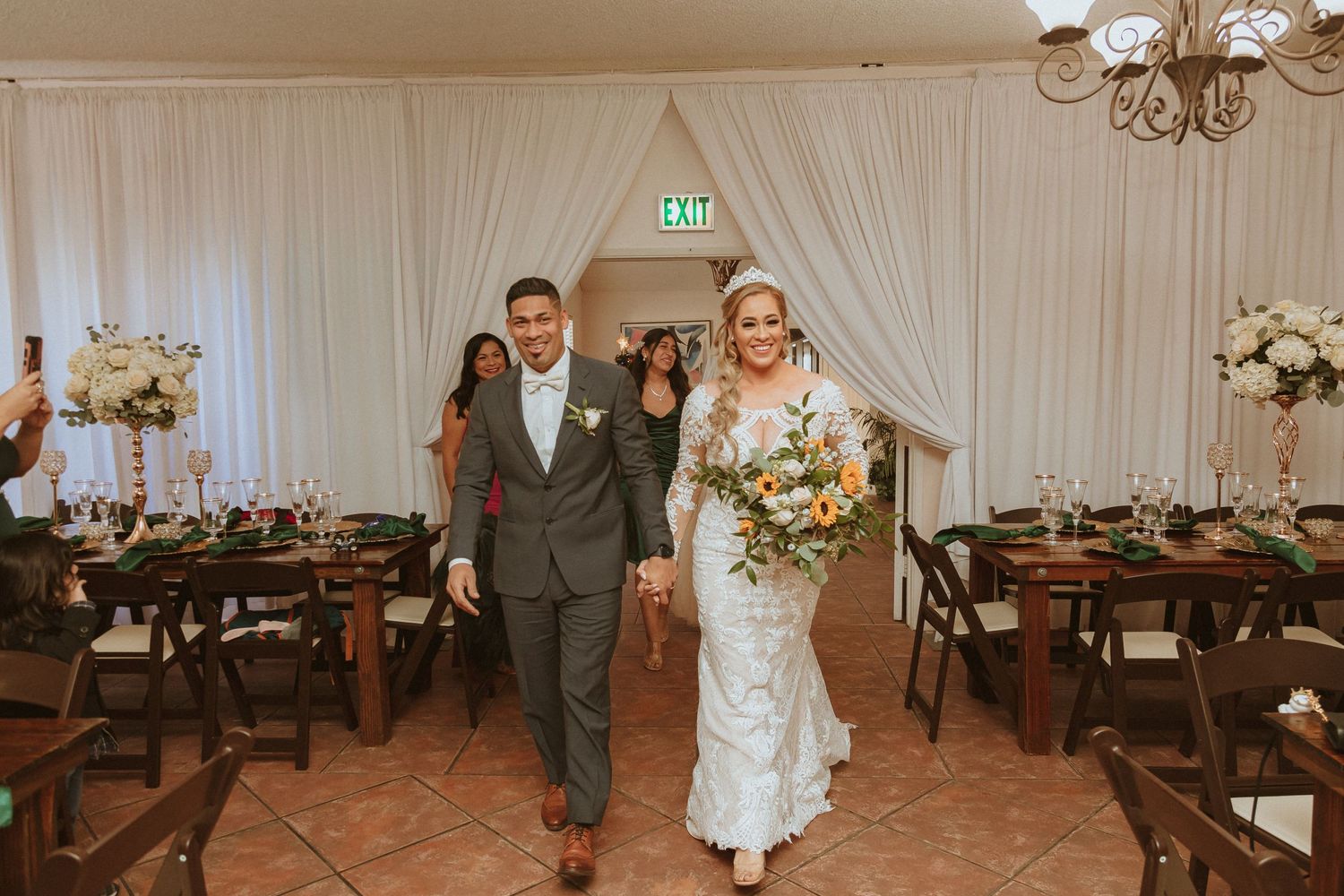 A couple makes their grand entrance through white draped doorways at their wedding reception.