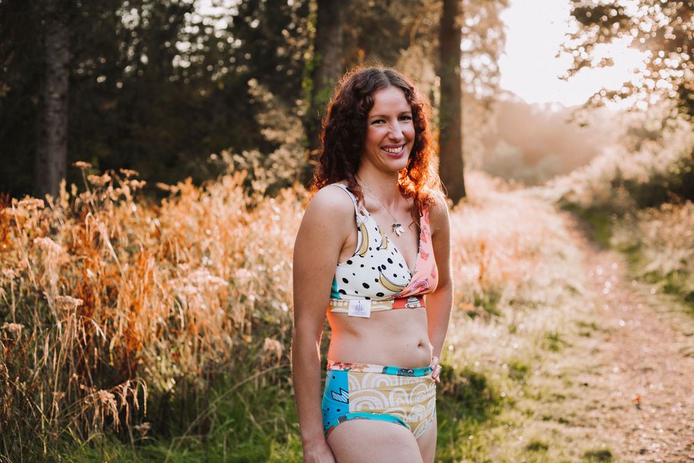 Sunlit outdoor scene showing people in colorful swimwear on a wooded path.