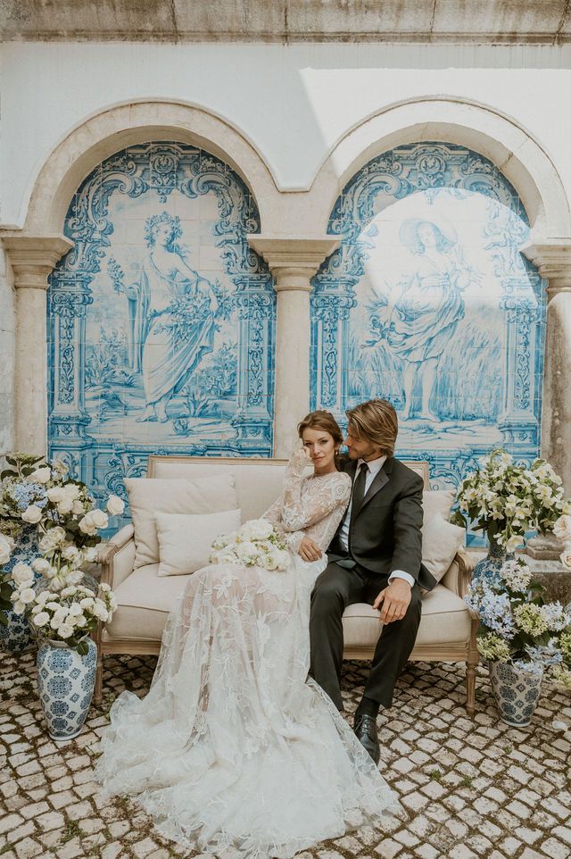 Couple posing in front of blue Portuguese azulejo tiles with vintage-inspired decor at elegant wedding venue.