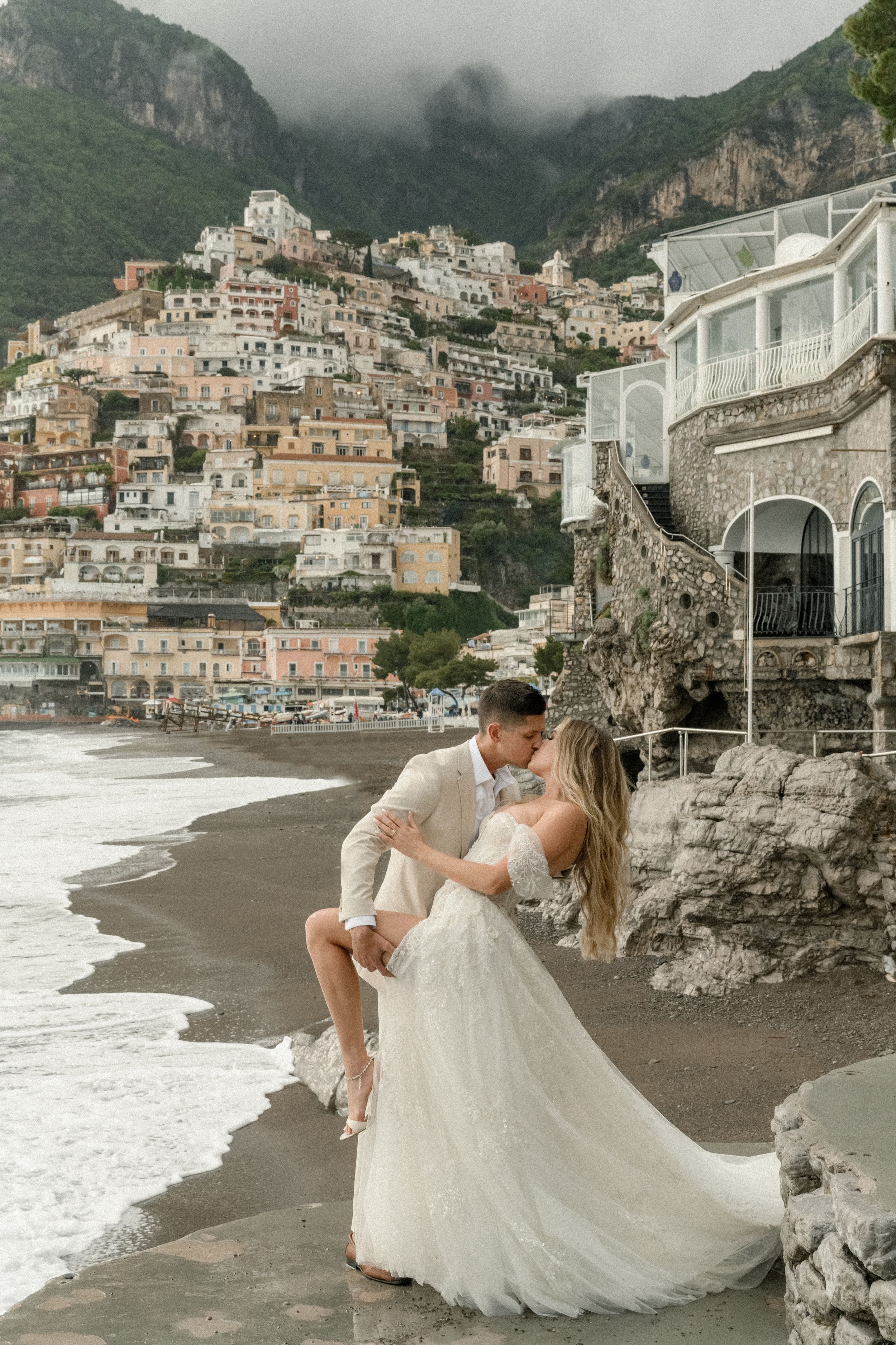 A cliffside wedding portrait with the iconic Positano village cascading down to the beach behind.