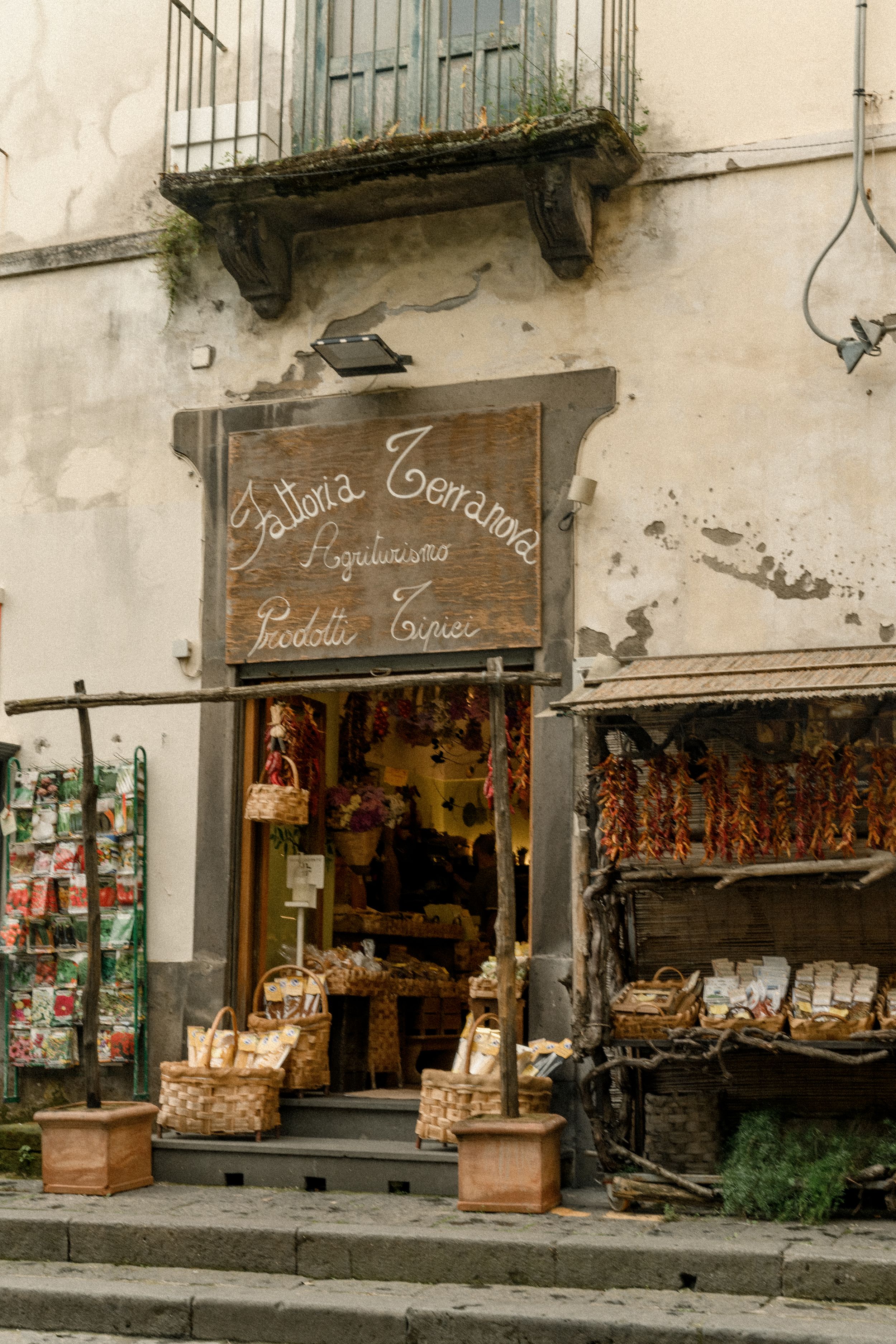 Traditional Italian delicatessen storefront with hanging meats and local products displayed.