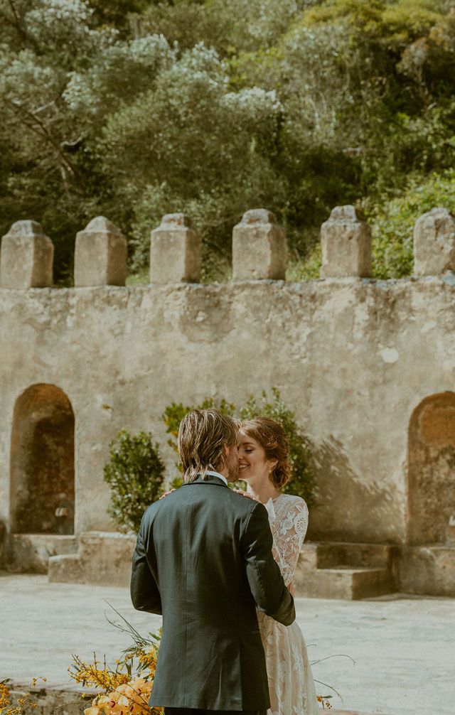 Wedding ceremony moment against rustic stone wall with castle-like architecture.