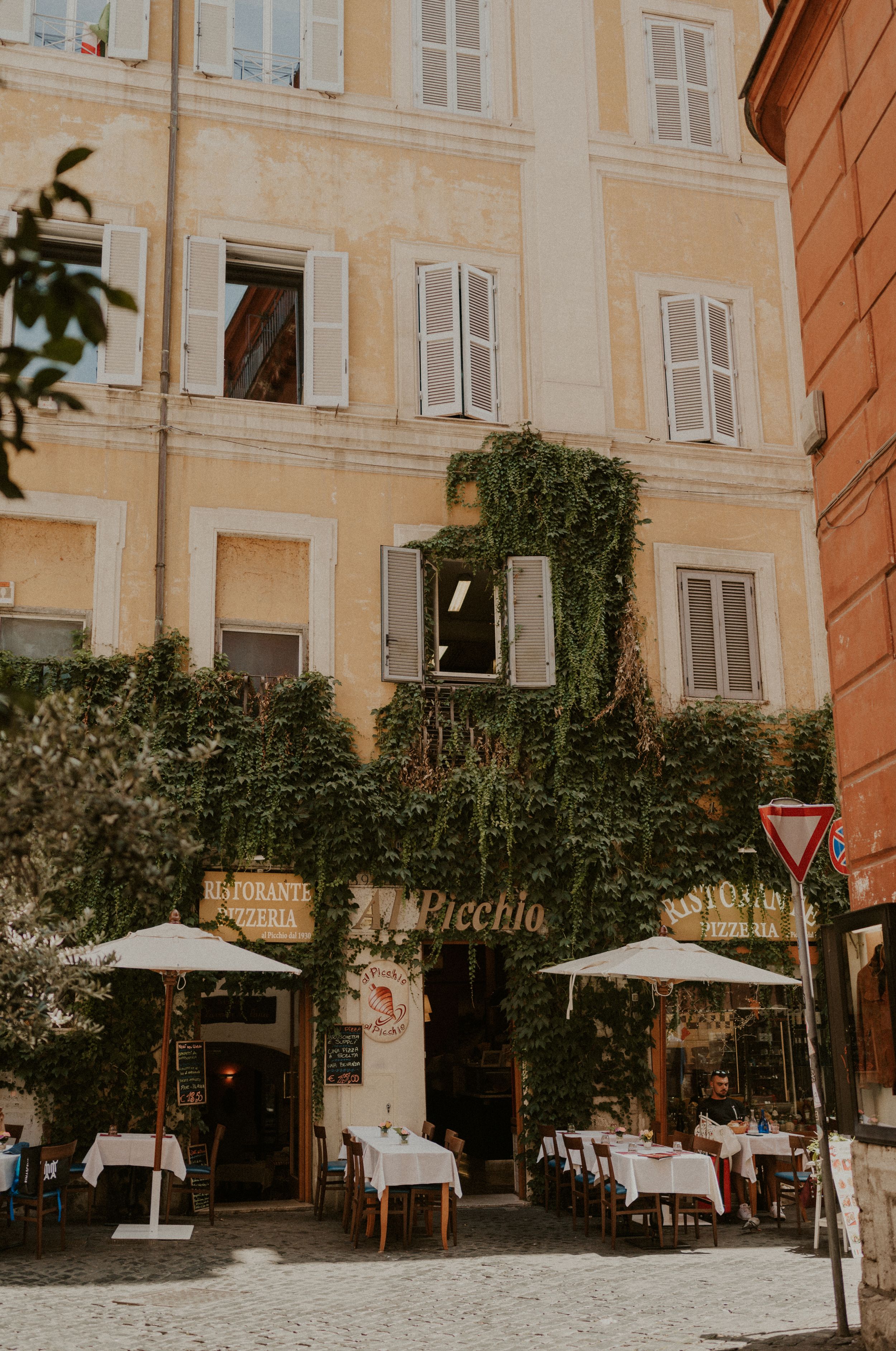 Charming Italian restaurant with outdoor seating and ivy-covered facade in Rome.
