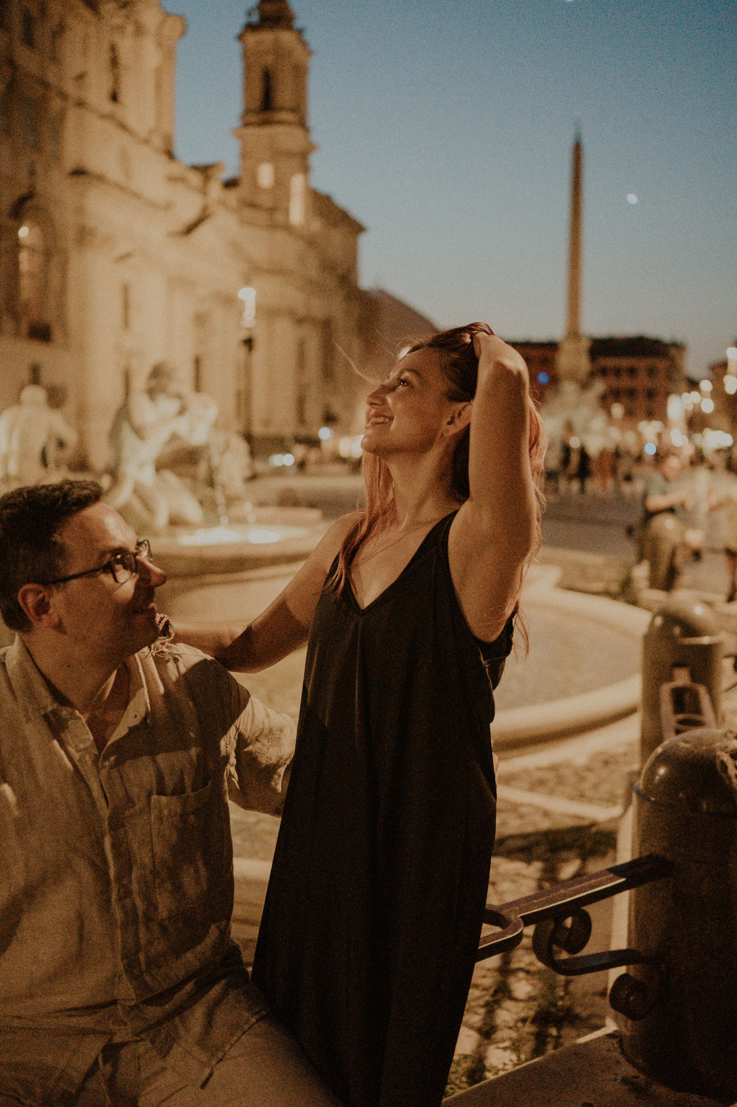 A joyful evening moment shared at Piazza Navona with illuminated baroque architecture in the background.
