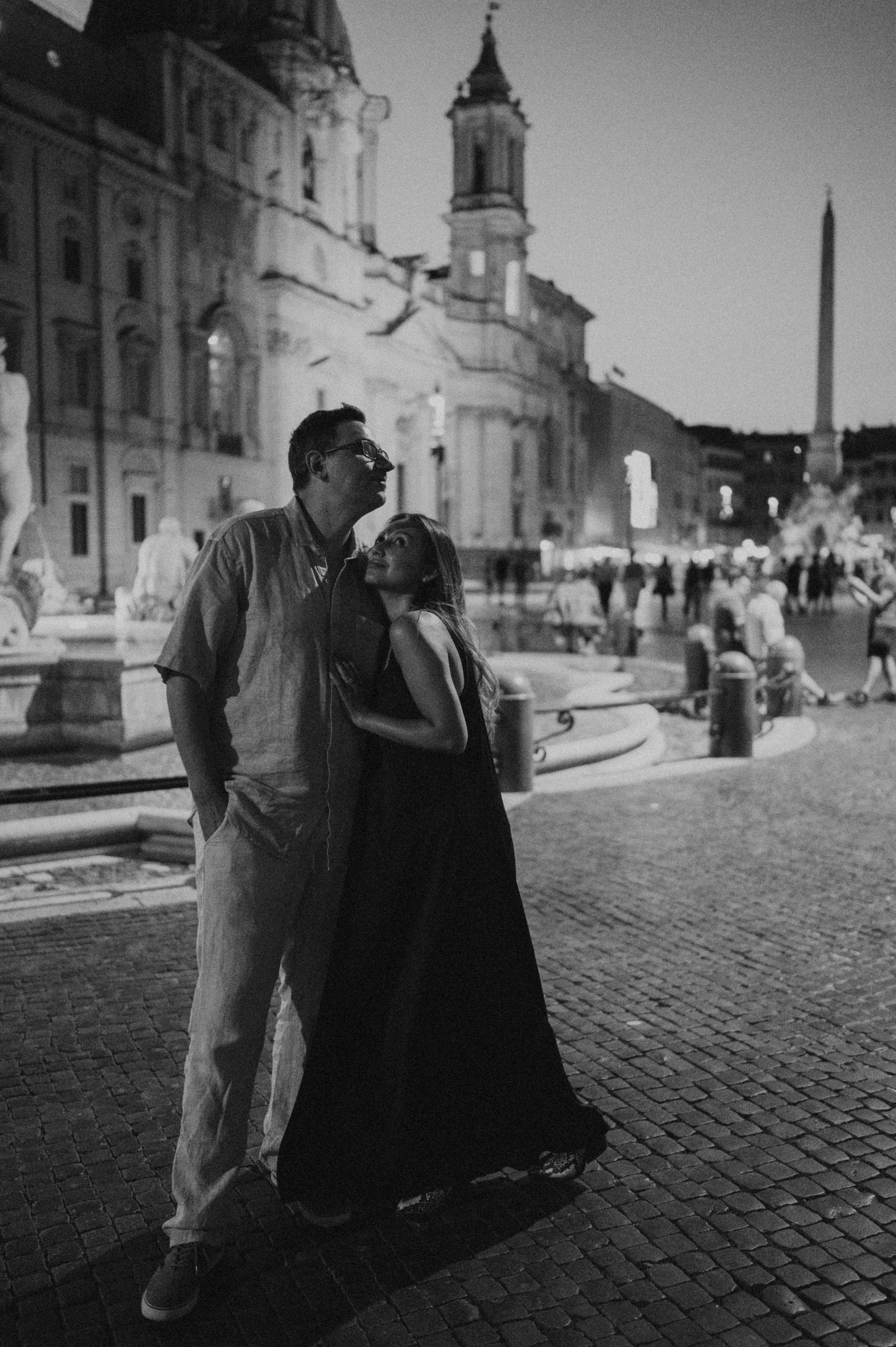 A black and white romantic moment captured in front of a historic church in Rome's Piazza Navona.
