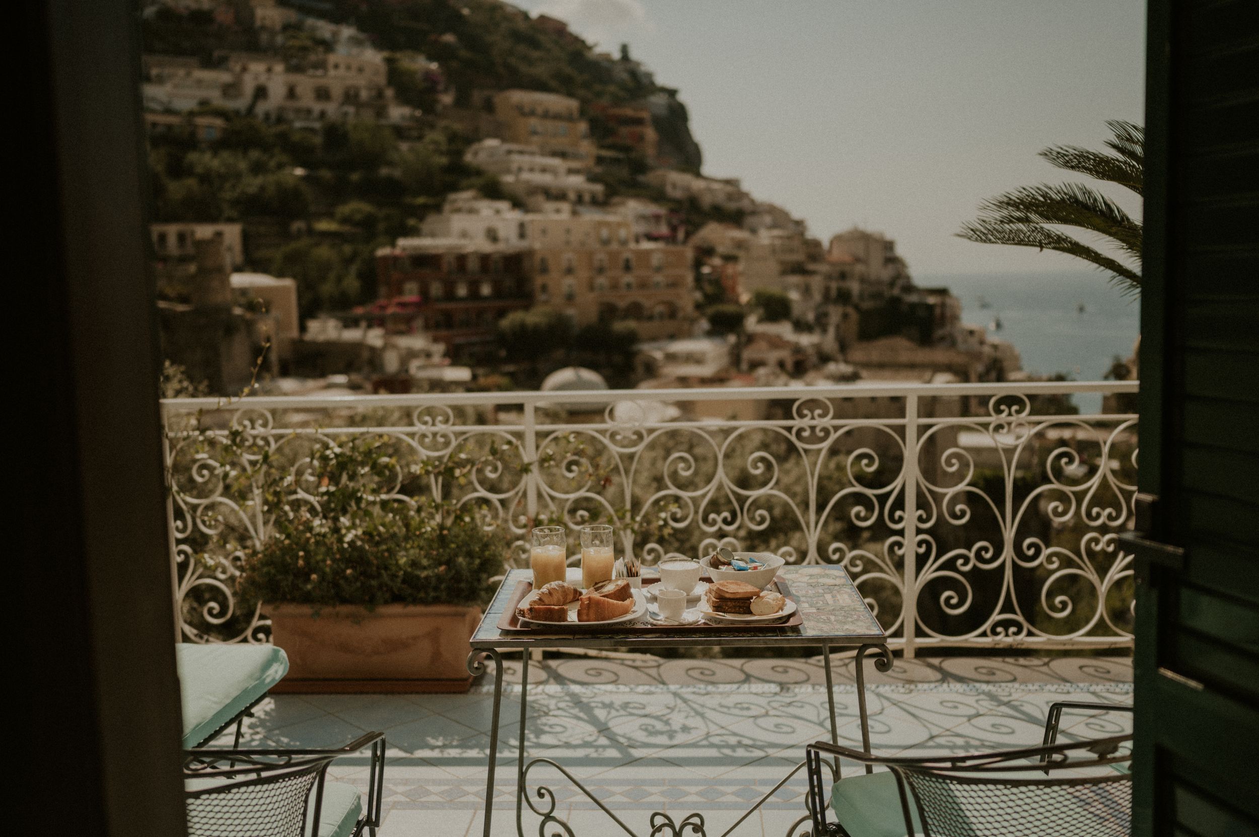 Breakfast table on a balcony overlooking the terraced buildings of Positano.
