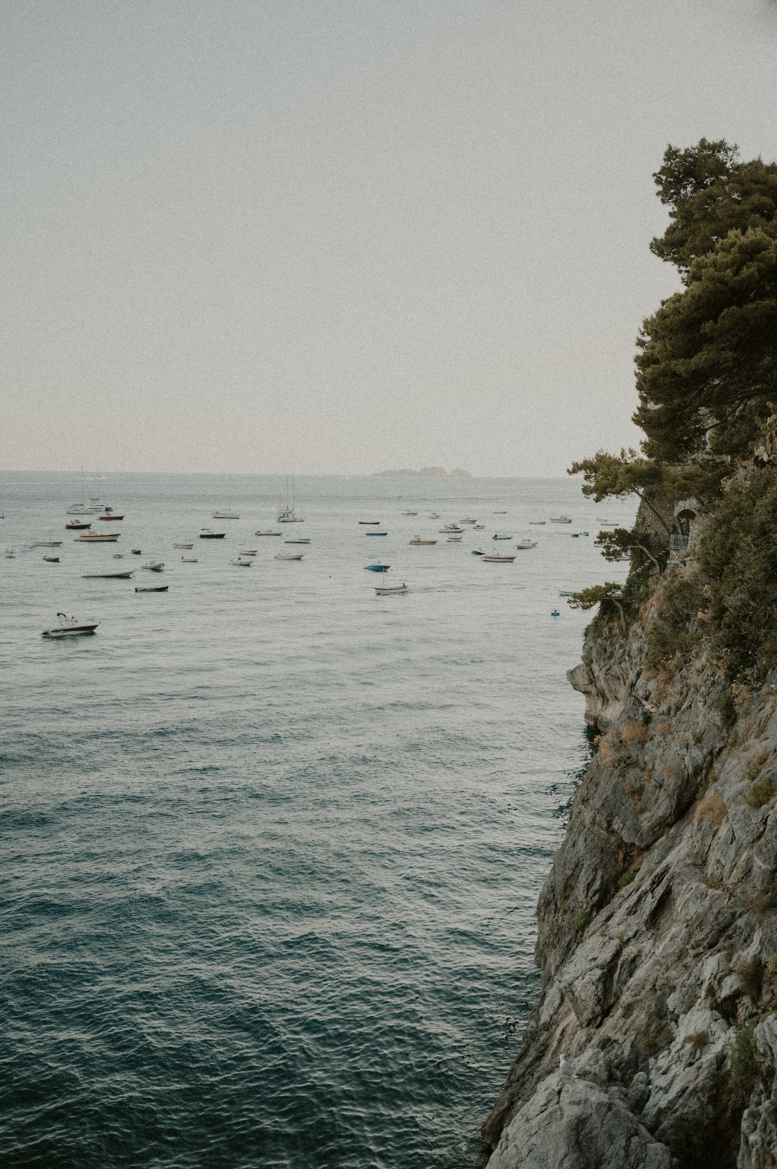 Boats dotting the Mediterranean Sea near dramatic coastal cliffs along the Amalfi Coast.