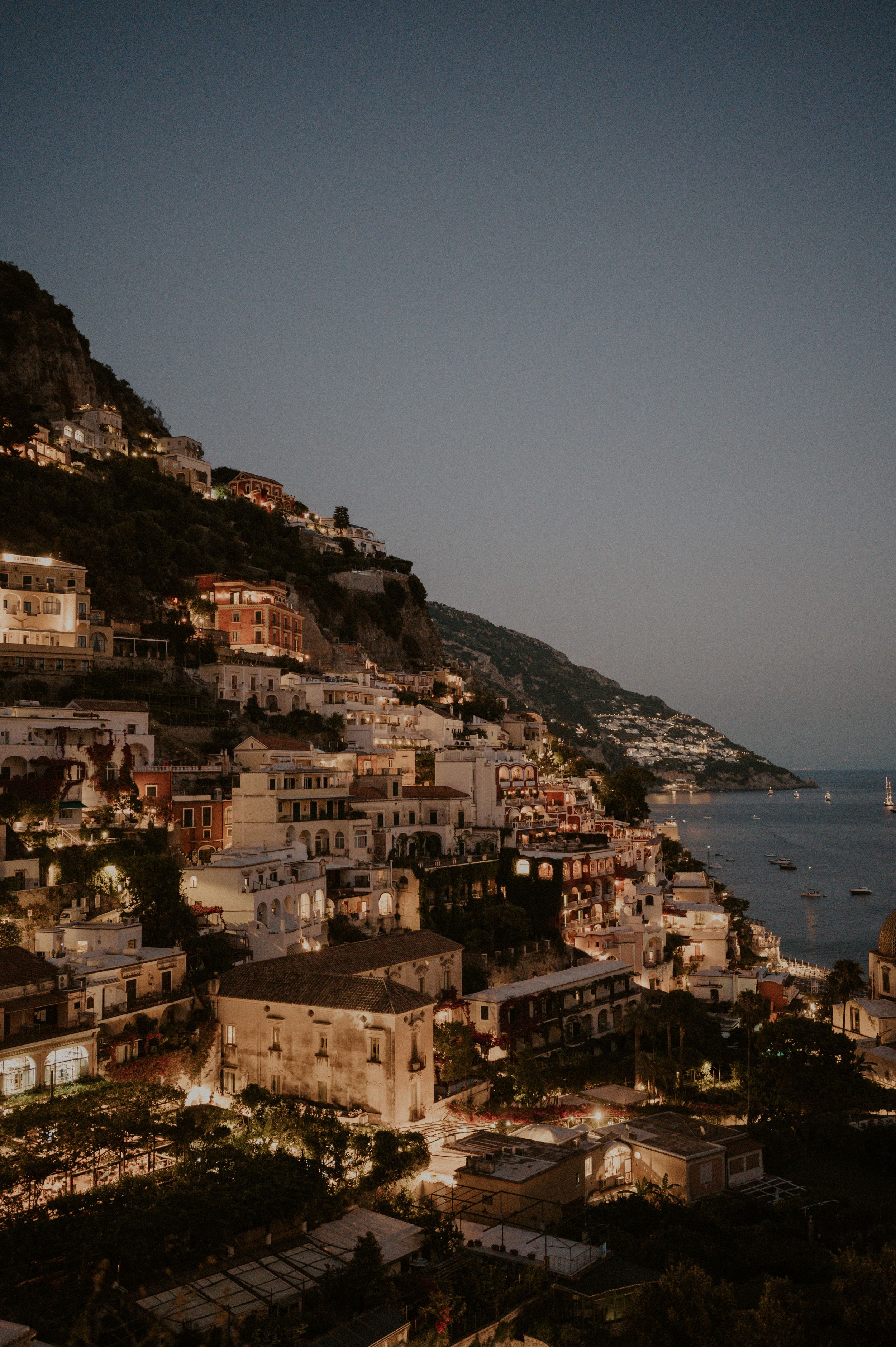 Evening view of Positano's illuminated coastal buildings cascading down the mountainside.