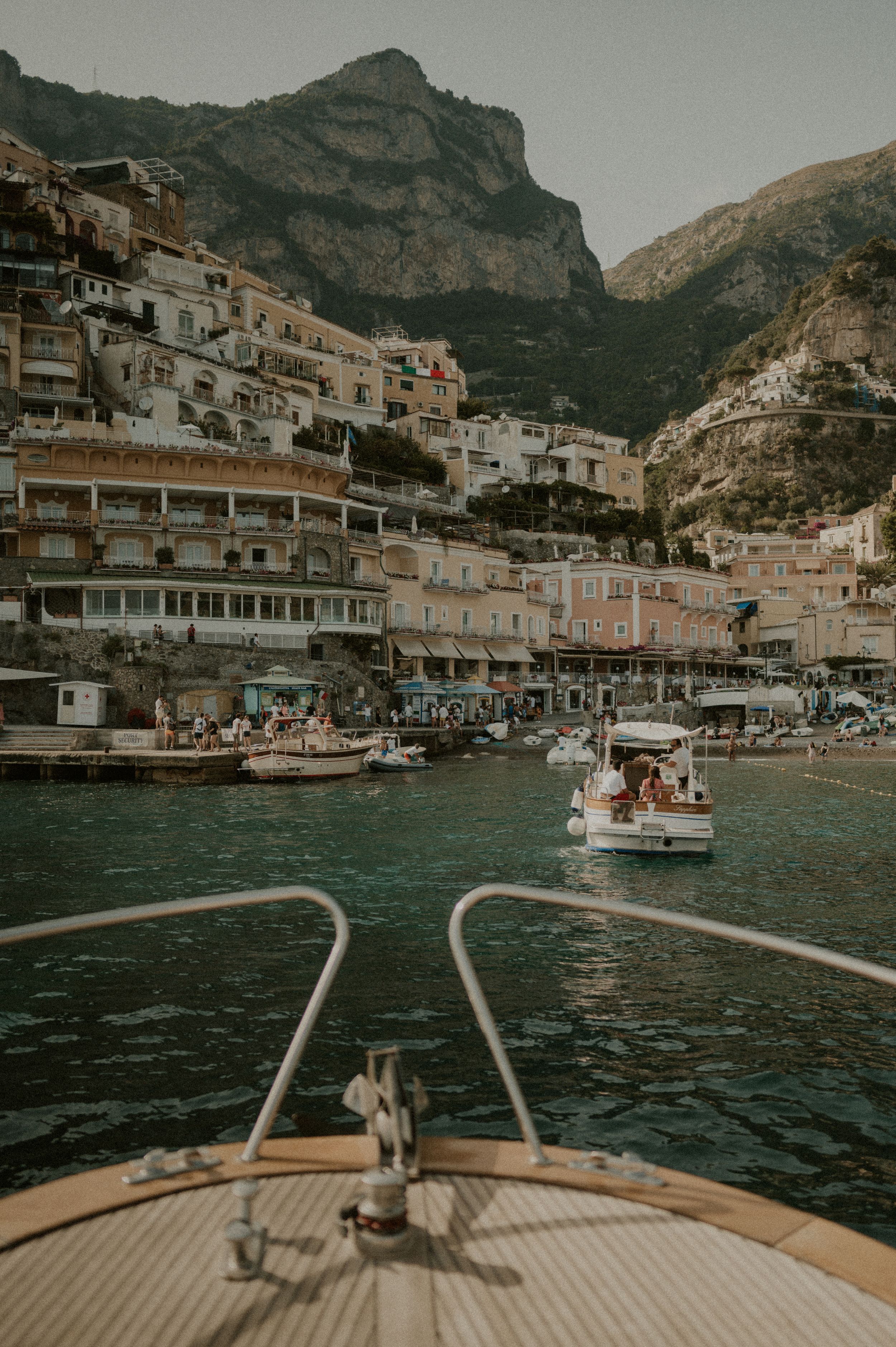 View from a wooden boat approaching Positano's harbor with traditional Mediterranean buildings stacked on the hillside.
