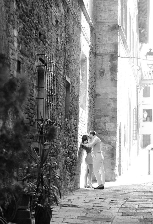Intimate moment captured in narrow European alleyway with stone architecture.