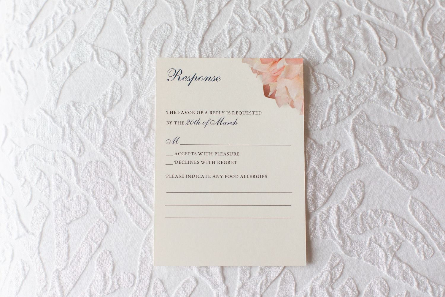 Wedding RSVP cards and response envelopes displayed on white textured surface.
