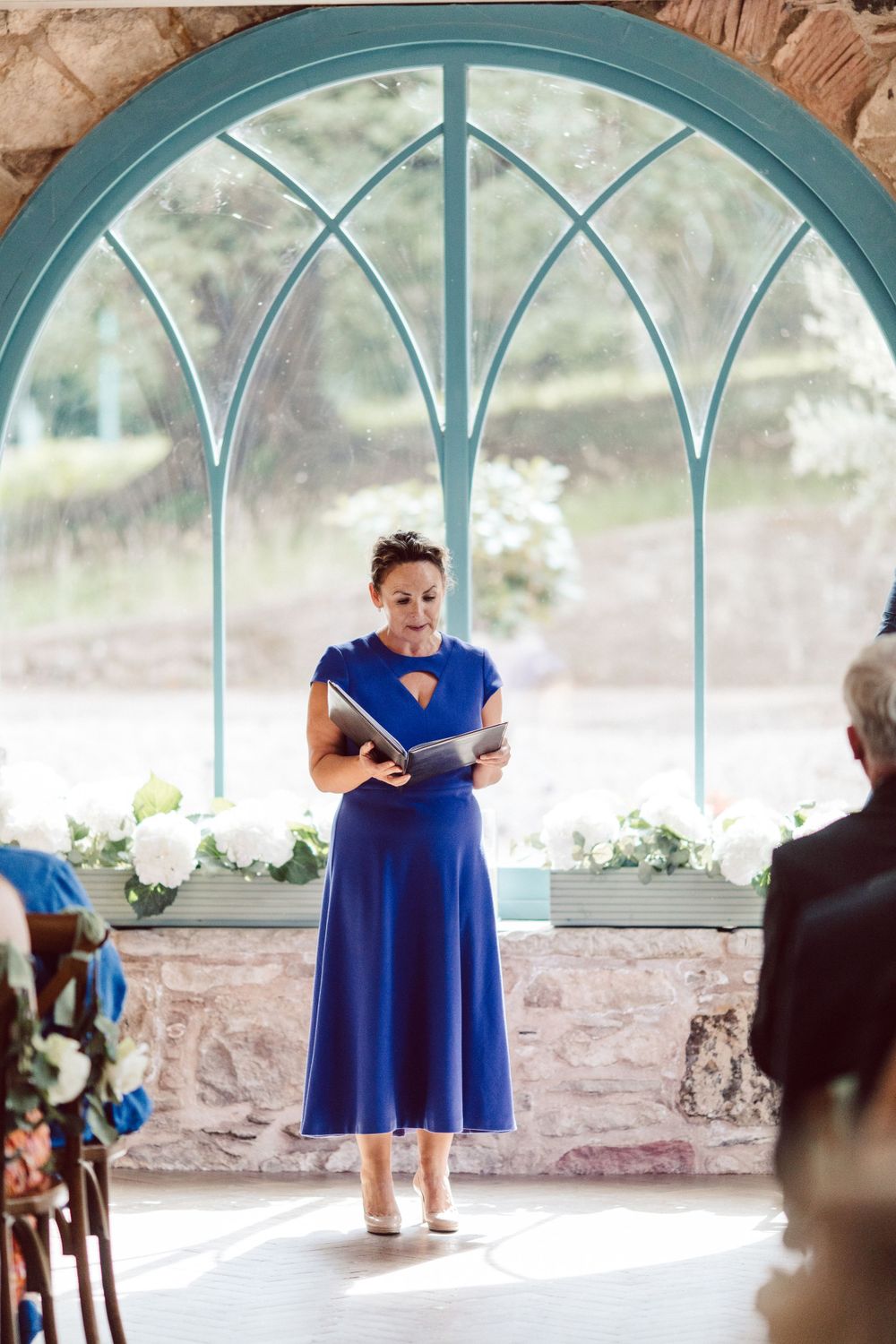 Stone chapel interior with blue arched windows and wedding decorations.