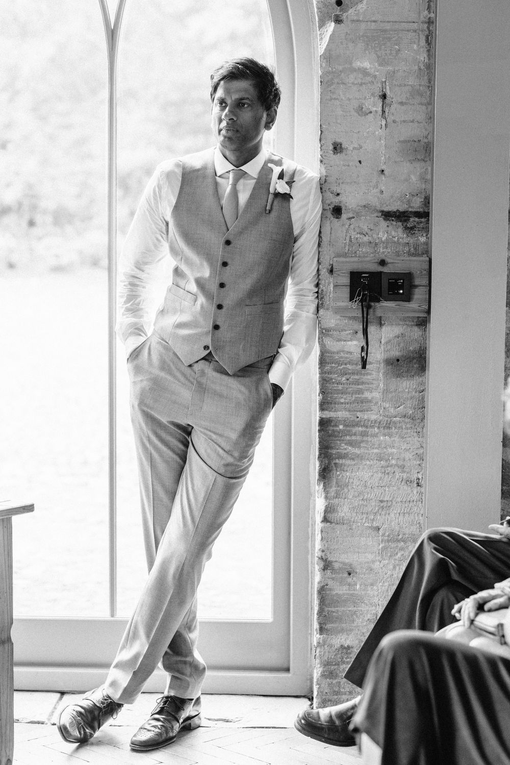 Light-filled venue with rustic stone walls and large windows creates dramatic wedding ambiance.