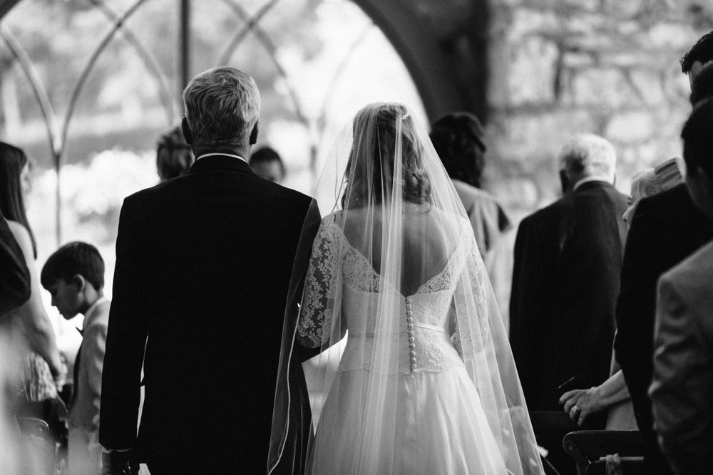 Wedding guests watching a ceremony in silhouette against a bright background.