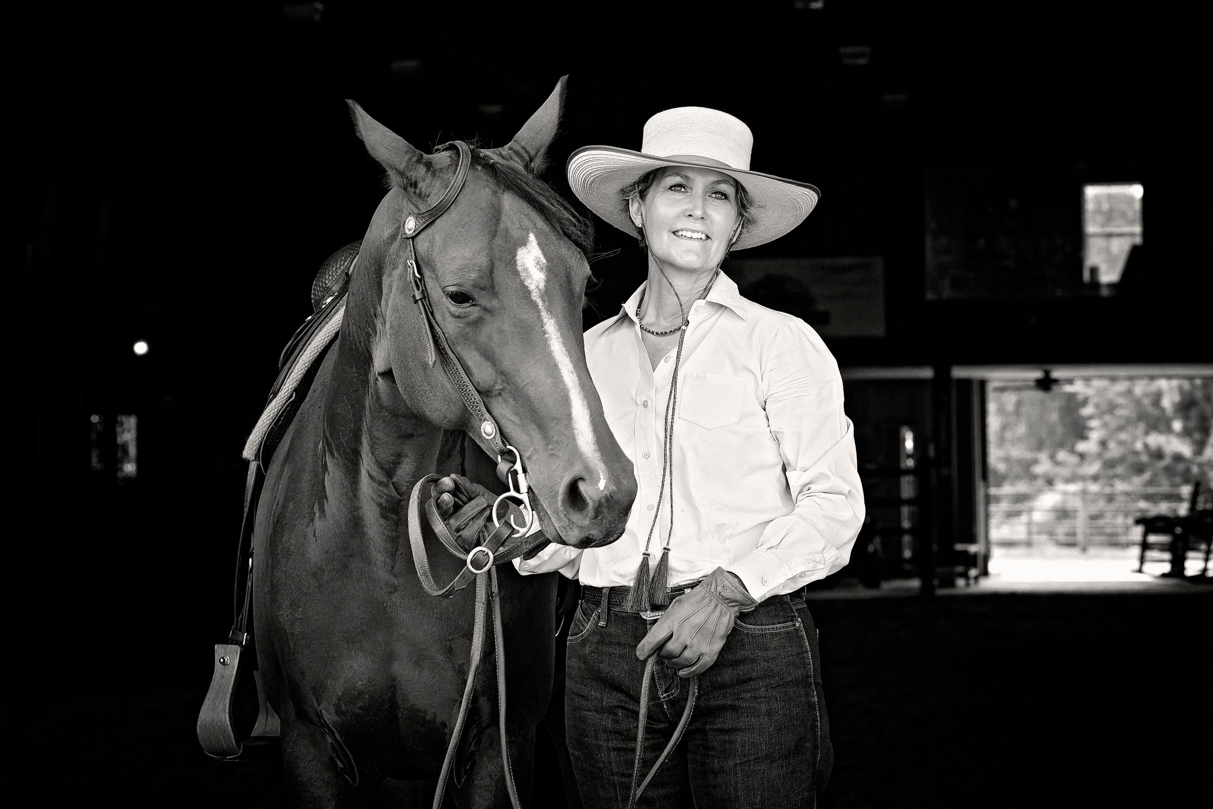 Woman and horse posing in barn in black and white