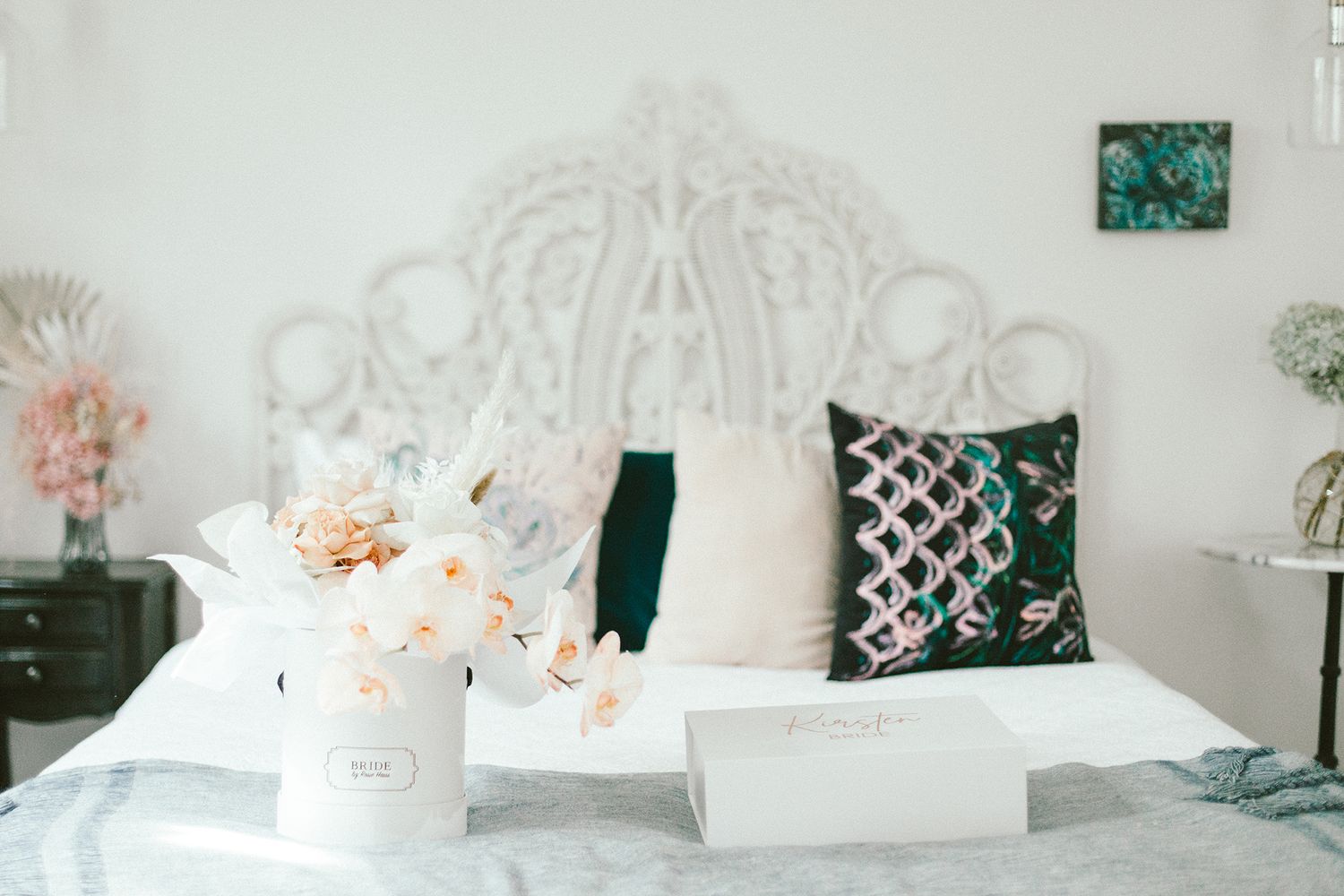 Elegant bedroom setting with white ornate headboard and decorative pillows.