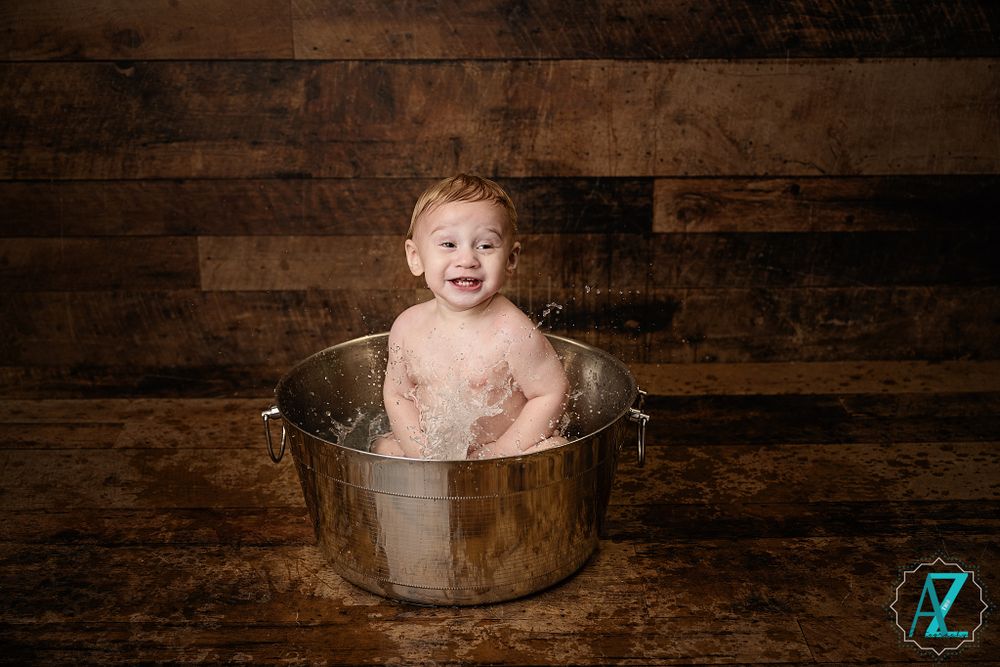 Portrait of a bath time moment in a vintage metal tub against rustic wooden background.