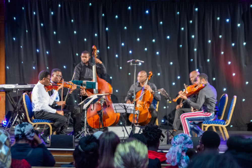 String quartet performing on stage with starry backdrop at evening concert event.