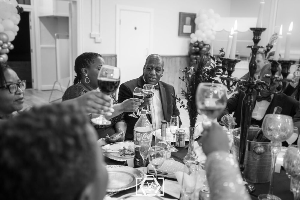 Guests raise glasses in a toast at an elegant formal dinner party celebration.