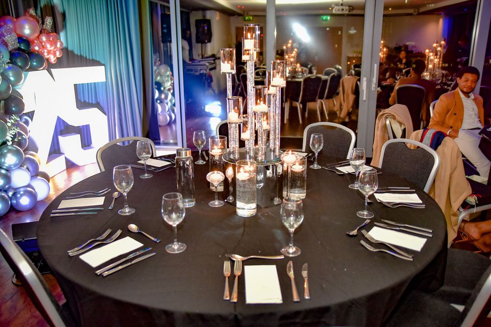 Elegant round dining table set with candles and glassware at a formal 75th birthday party.