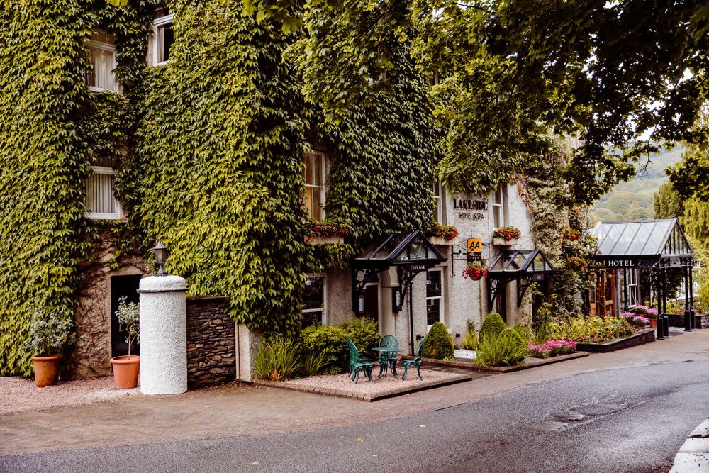 Charming street view of a building covered in lush green ivy with a white pillar in front.