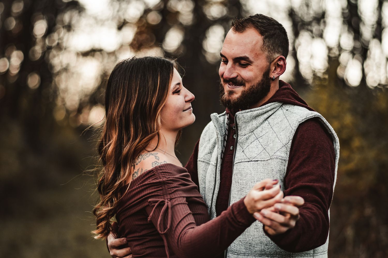Couple dancing and laughing together in casual autumn wear with bokeh background.