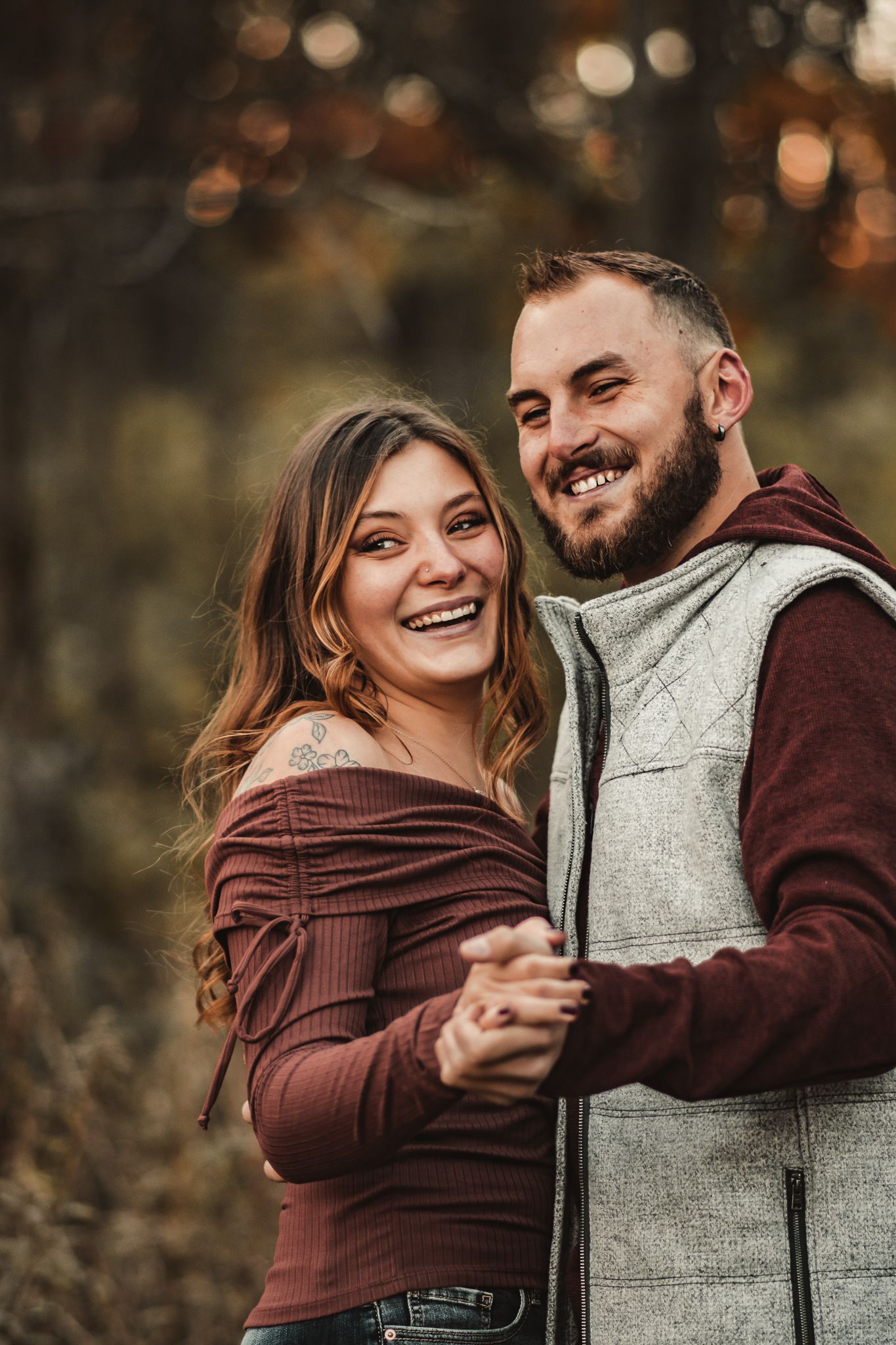 A romantic autumn portrait of a couple laughing and embracing outdoors with bokeh lighting.