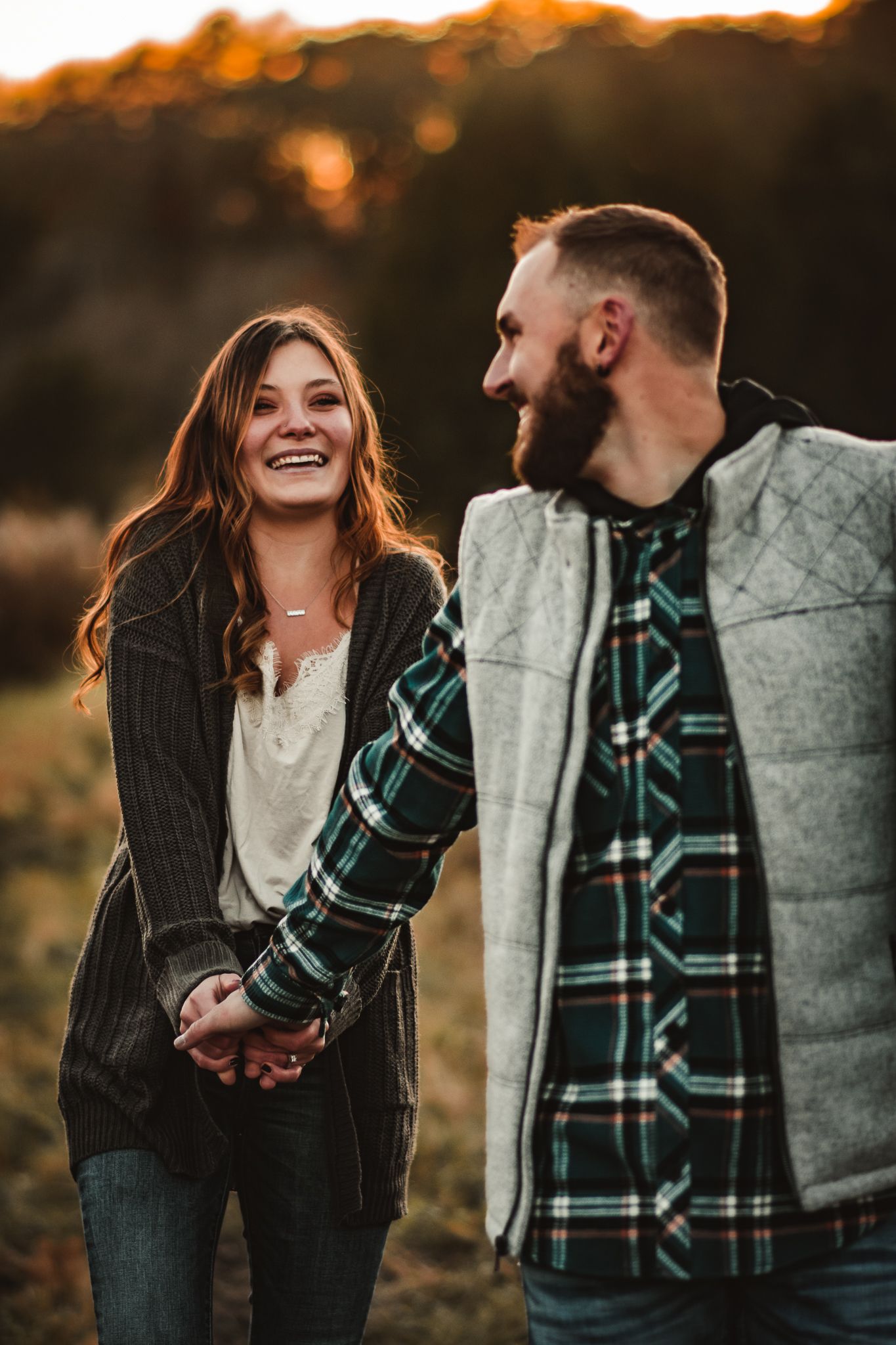 A joyful couple sharing a laugh during sunset in casual fall attire.