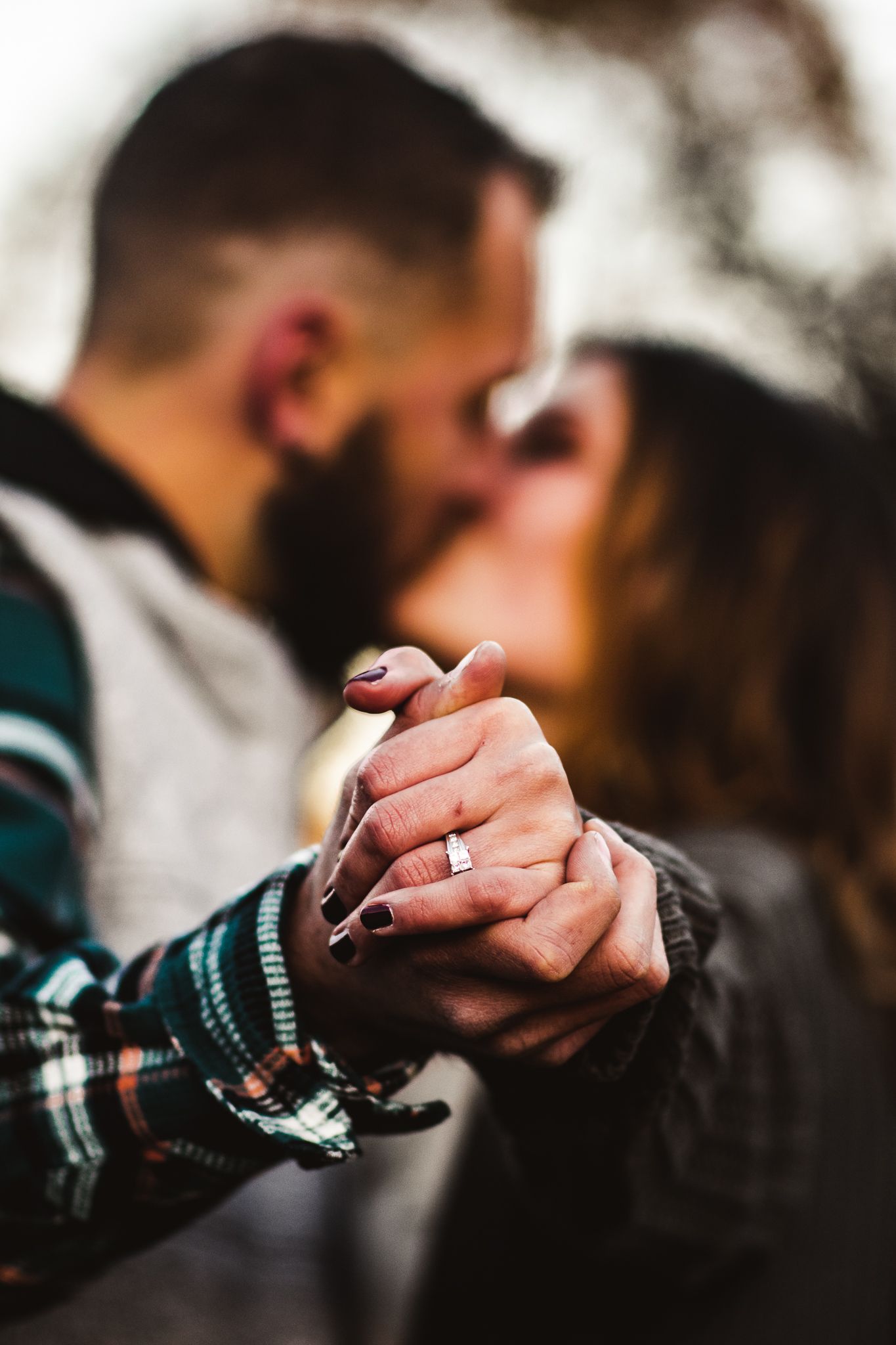 A close-up shot of intertwined hands with an engagement ring during an intimate moment.