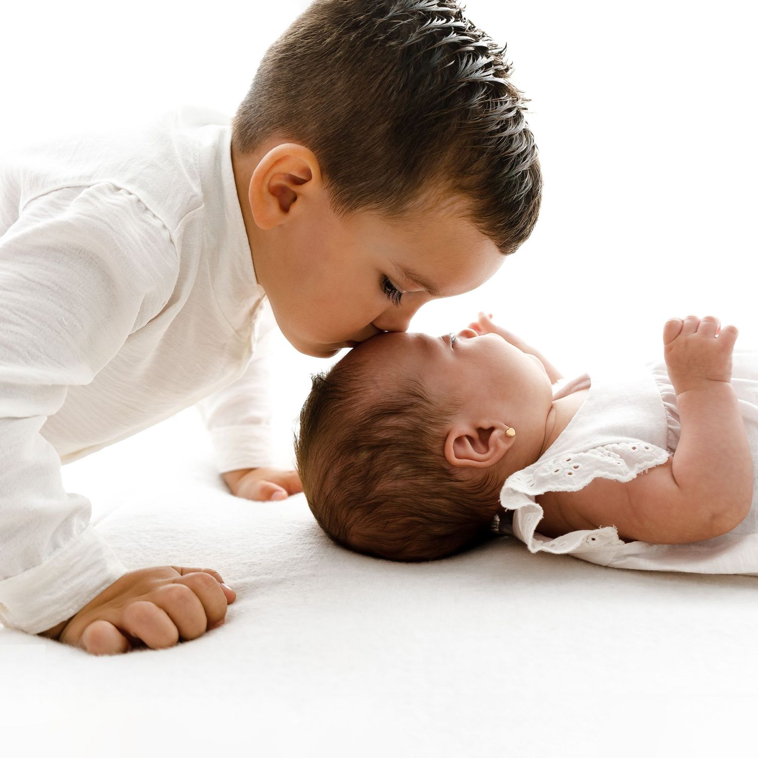 Tender sibling bonding moment on white background.