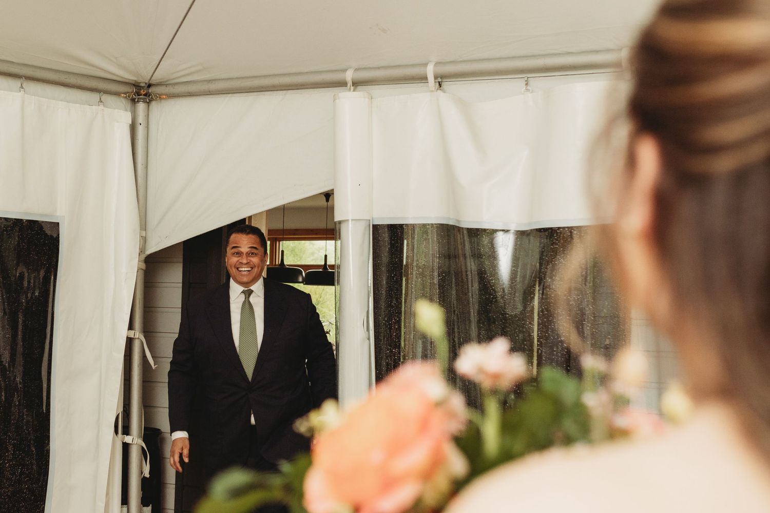 A formal gathering moment captured under a white tent during an outdoor event.