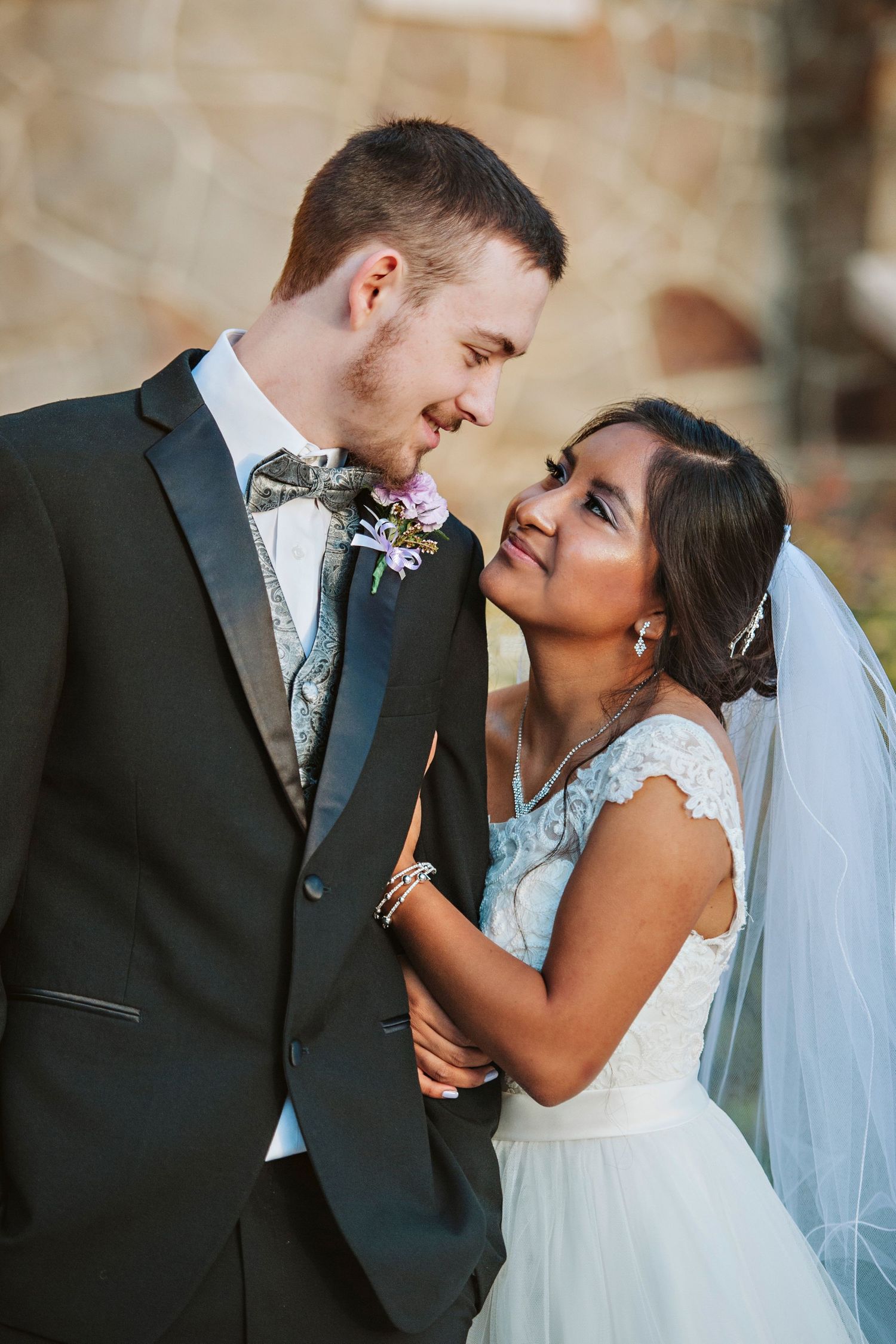 Bride and groom gaze at each other and smile in a classic wedding portrait